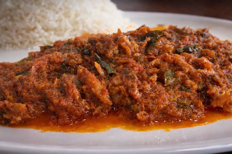 Haitian red snapper in rich tomato sauce with green vegetables, served with white rice.